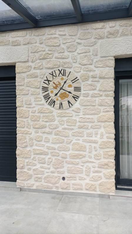 Travaux d'enduit mural imitation pierre dans une véranda, avec horloge intégrée gravée, près de Dreux