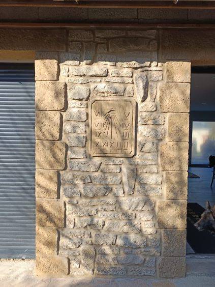 Création d'un mur de pierres artificielles sur une façade de maison avec gravure d'une horloge égyptienne près de Saint-Lô