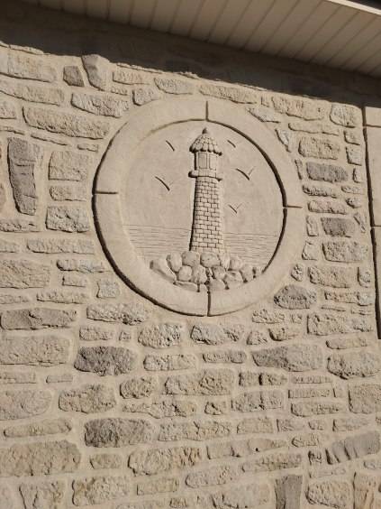 Création d'un mur de pierres artificielles en enduit décoratif à la chaux pour un ravalement de maison, avec sculpture d'un phare, près de Saint-Lô dans la Manche
